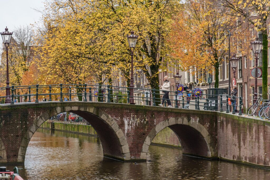 Stone canal bridge with autumn trees in Amsterdam